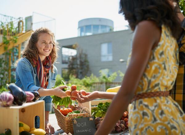 Two people buying vegetables from outdoor market